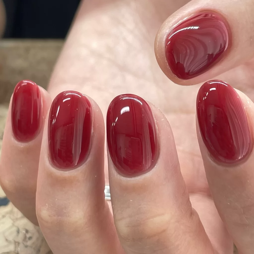 Glossy red jelly nails manicure showing transparent glass-like finish on natural nails