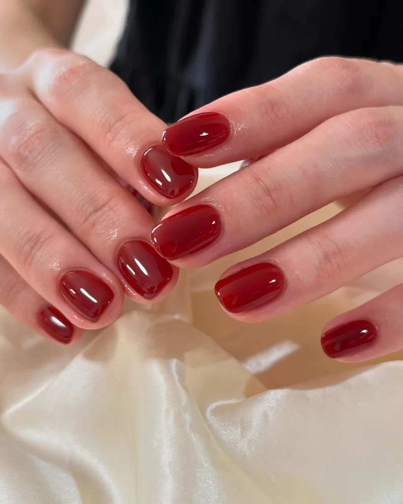 Glossy red jelly nails with glass-like finish on short natural nails