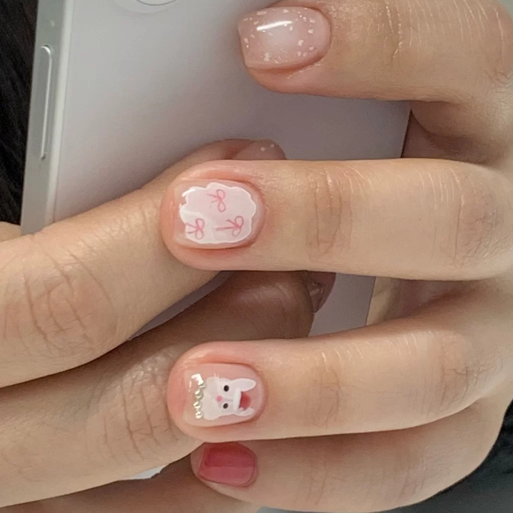 Korean gel nails with cute bunny and bow designs on neutral pink base