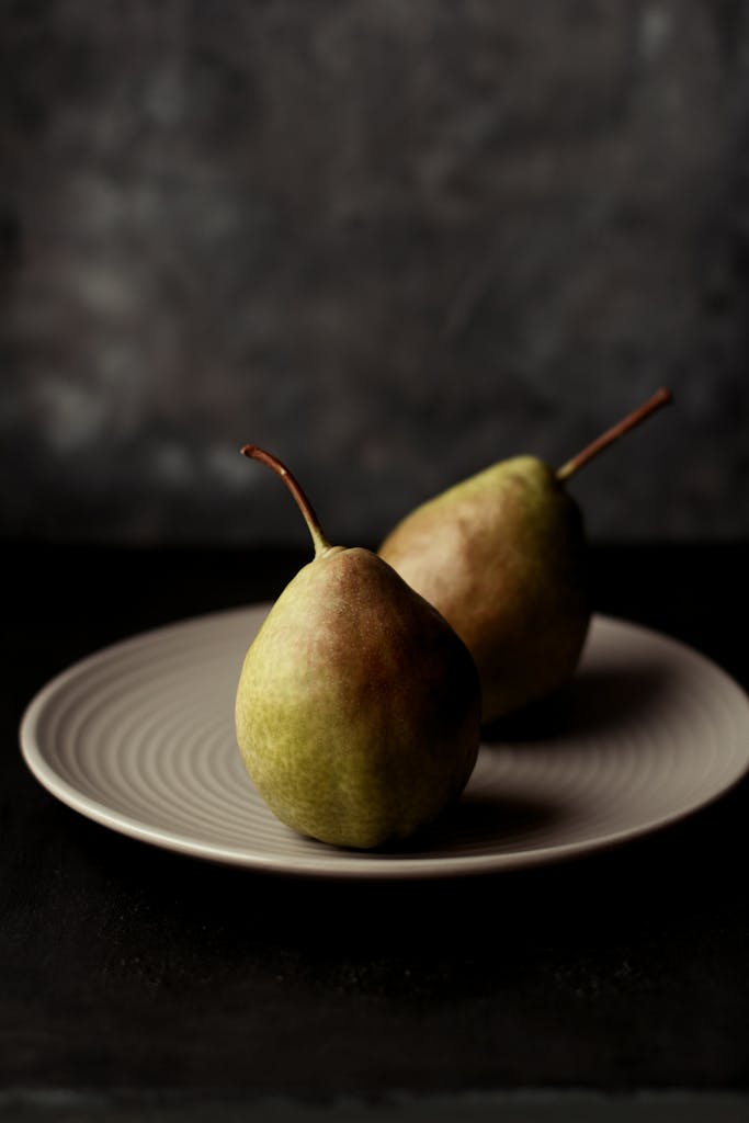 A minimalist still life featuring two ripe pears on a decorative plate.