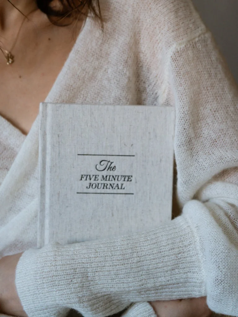 a person wearing white cardigan holding a journal