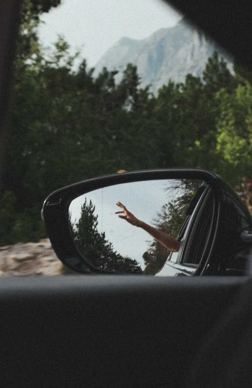 person s hand reflecting on car wing mirror