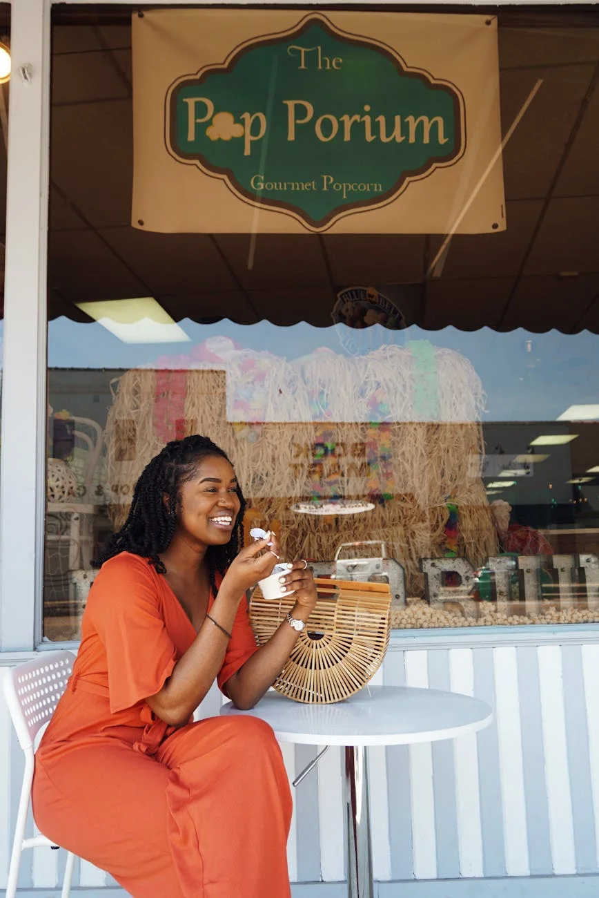 woman smiling and eating outside the pop porium shop