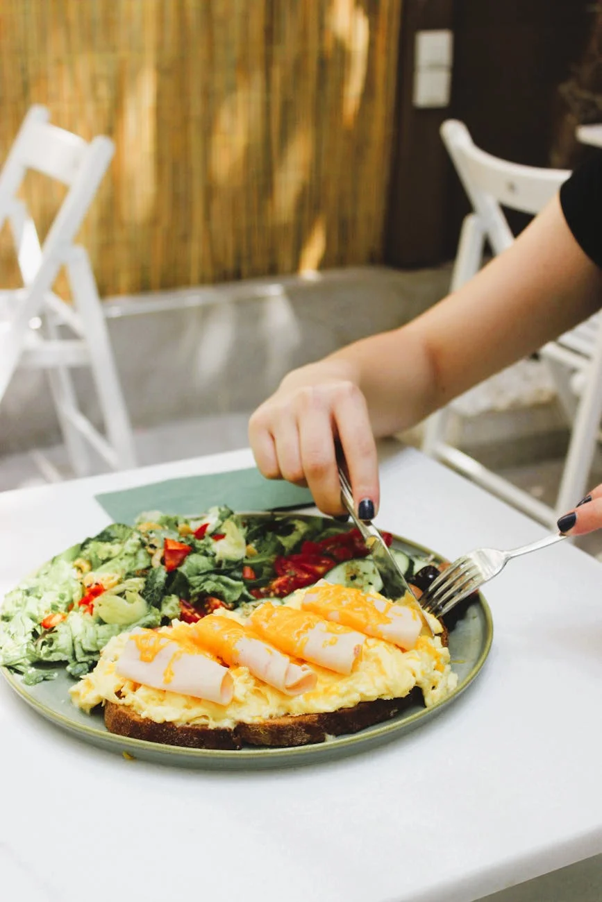 woman eating sandwich with fork and knife