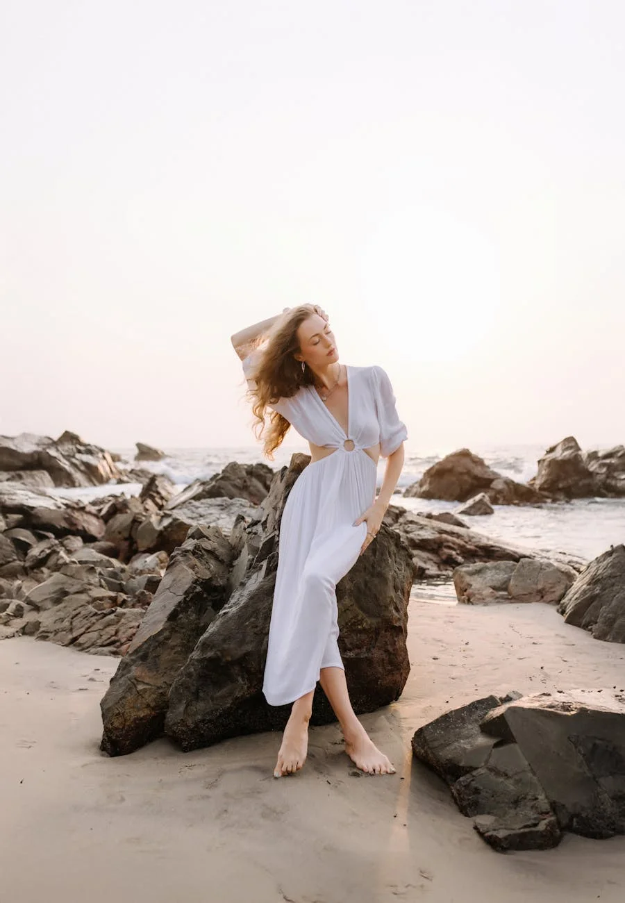 elegant woman in white dress on rocky beach