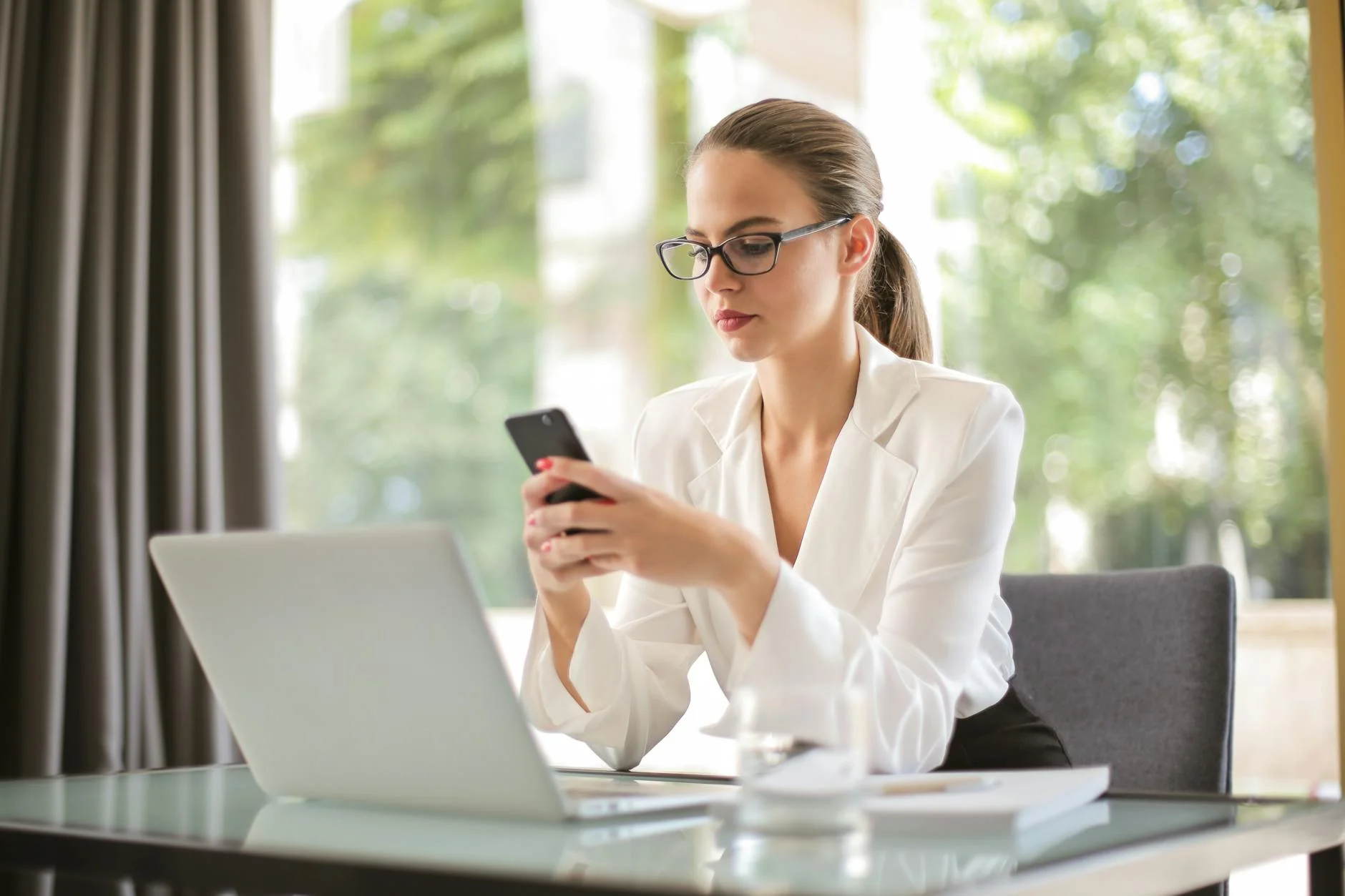 serious businesswoman using smartphone in workplace