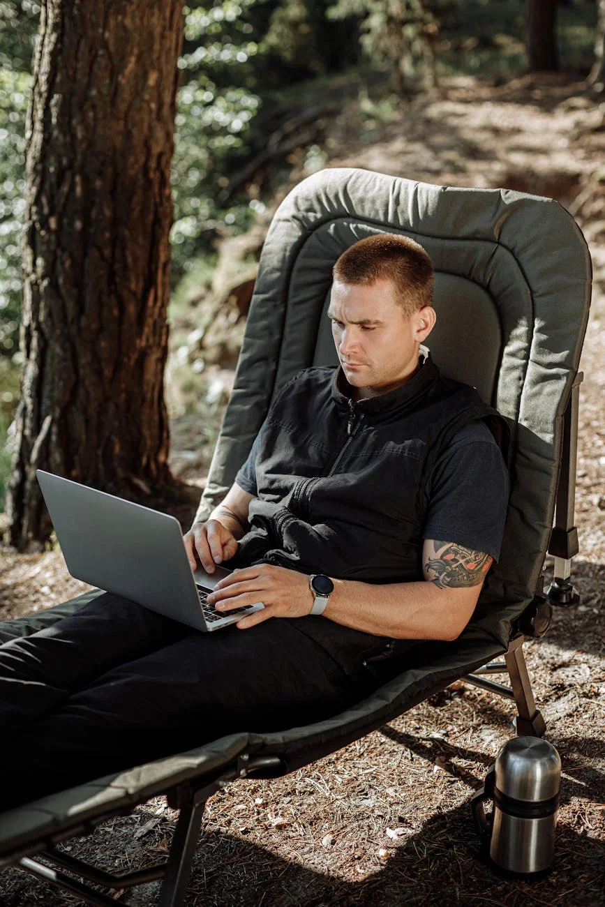 man in black dress shirt sitting on chair using macbook