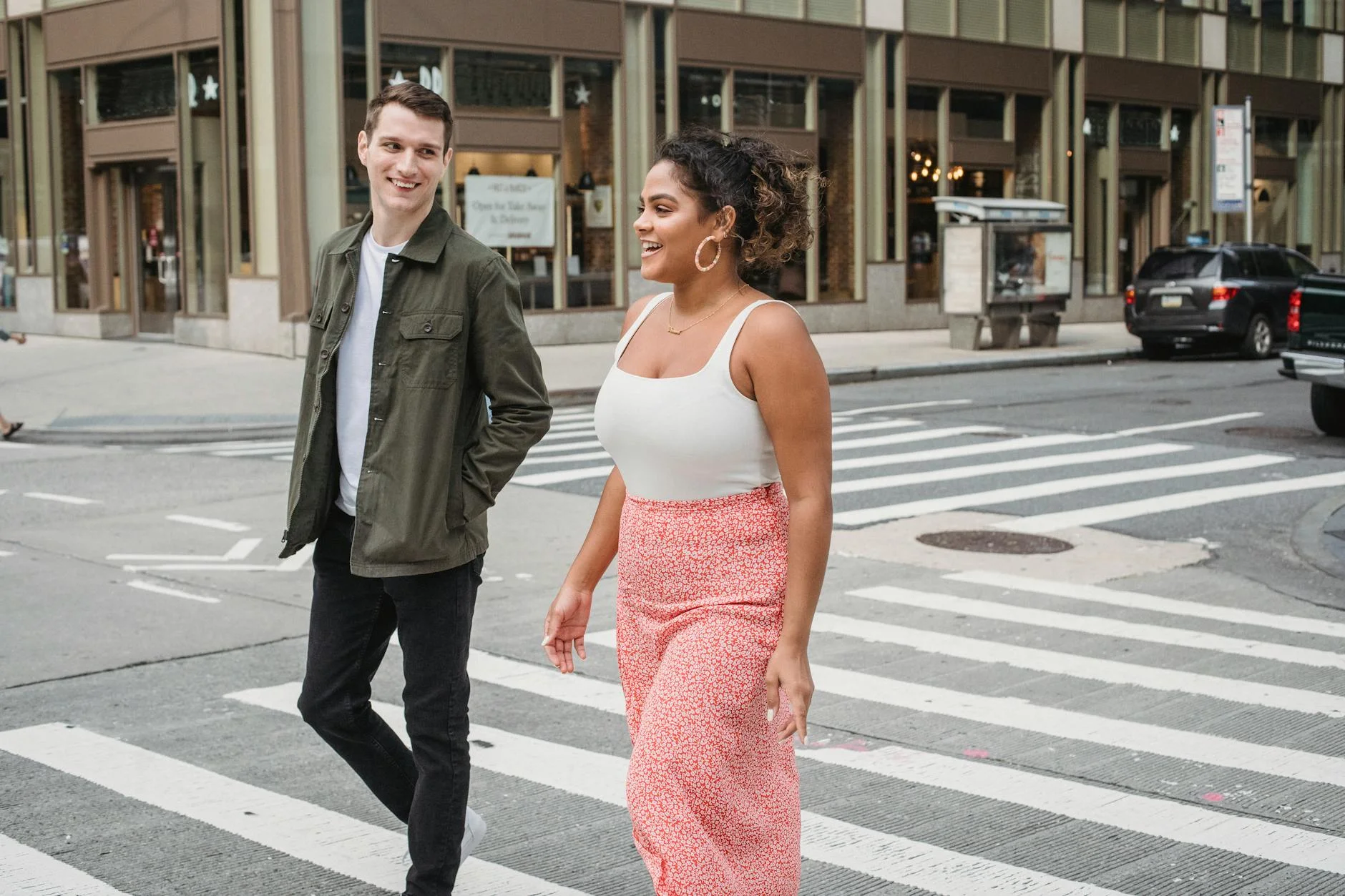 positive young diverse couple crossing road in downtown