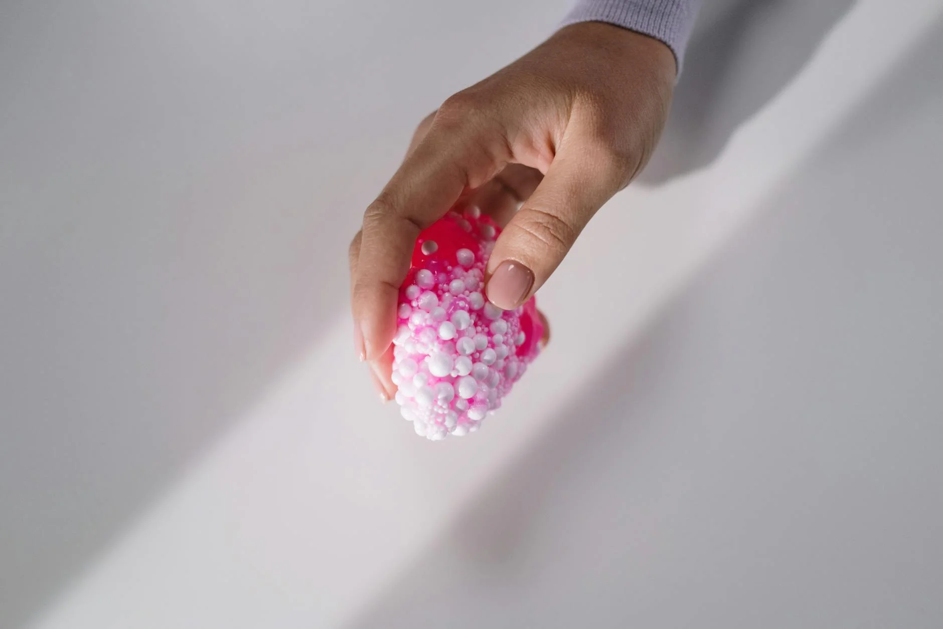 close up shot of a person holding a pink slime