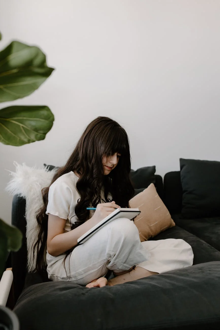 a girl with long wavy hair sitting on bed writing on notebook