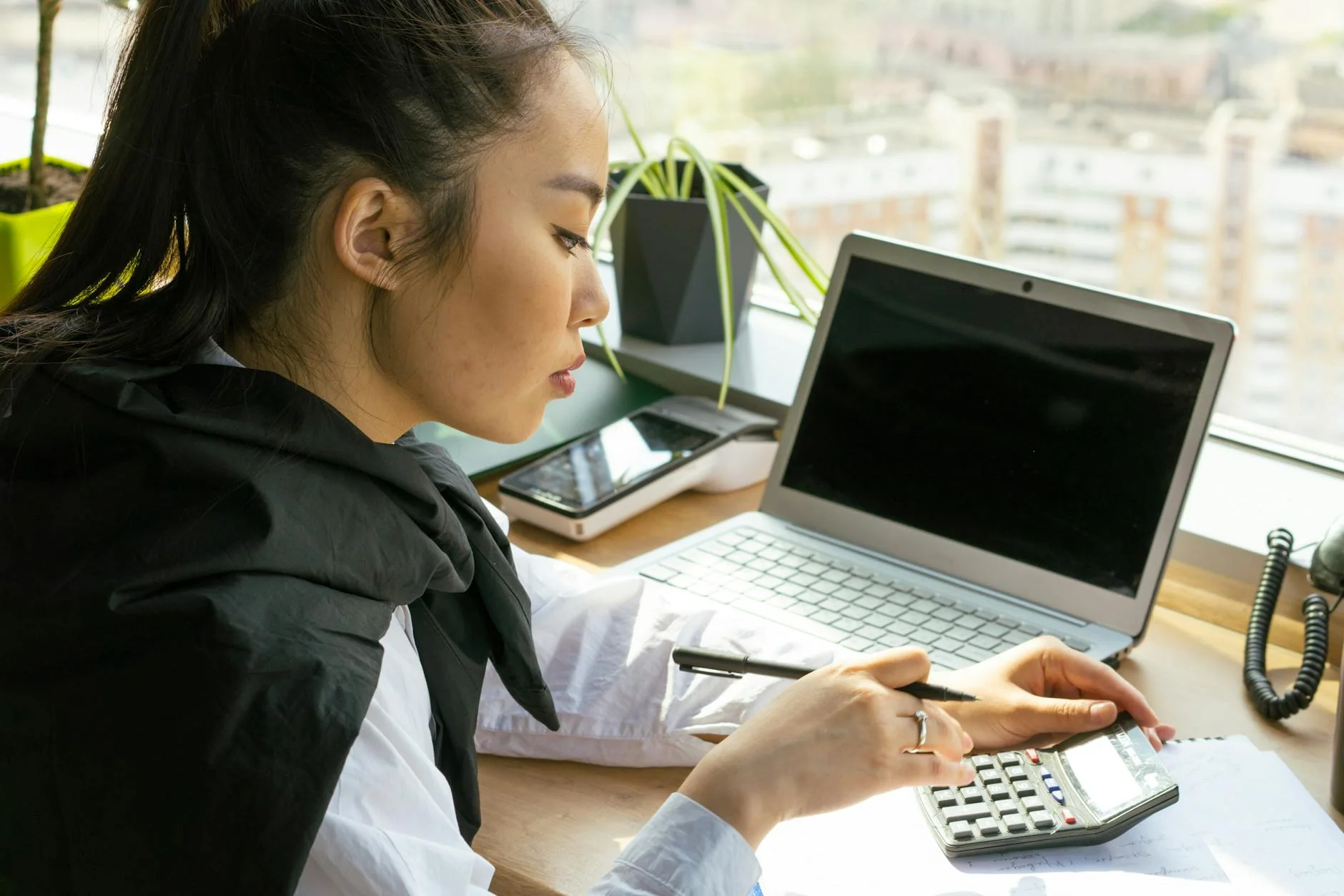 woman holding a black pen using a black calculator