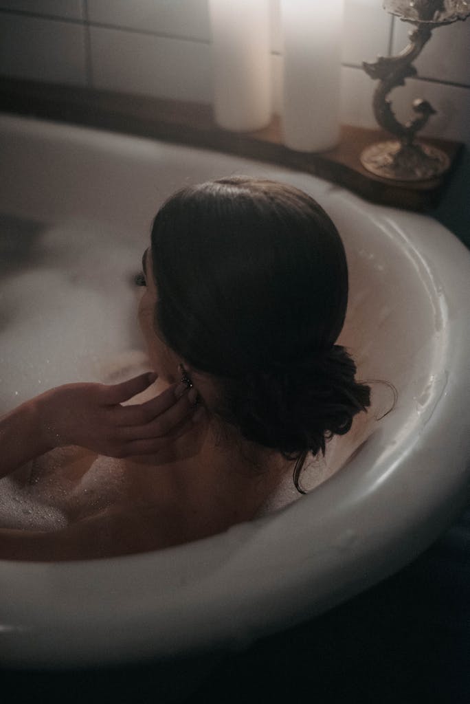 Woman enjoying a serene bath with warm candlelight ambiance.