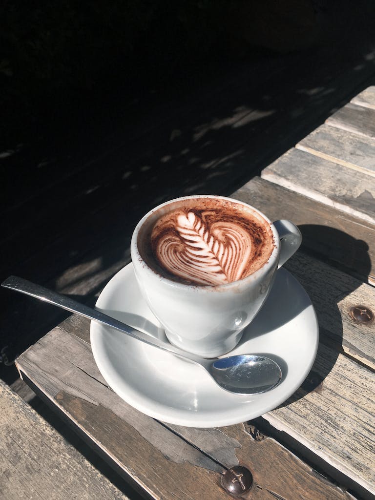 A beautifully crafted cappuccino with latte art on a rustic wooden table.