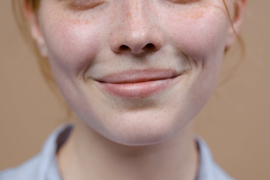 A close-up image capturing the subtle smile and freckles of a woman.