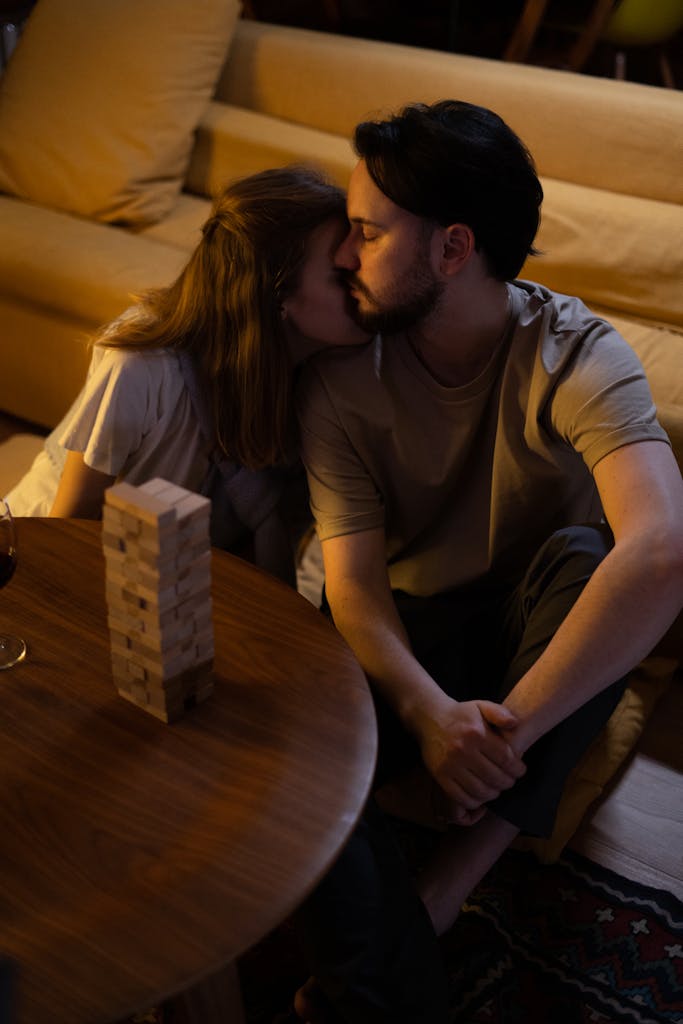 A couple embracing while playing a board game at home in a cozy setting.