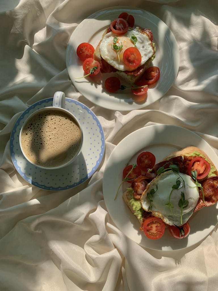A delightful flat lay of breakfast with bacon, egg toasts, and a cup of coffee on satin.