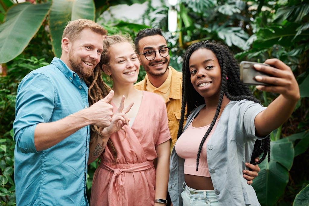 A group of diverse friends taking a cheerful selfie together in a lush outdoor setting.