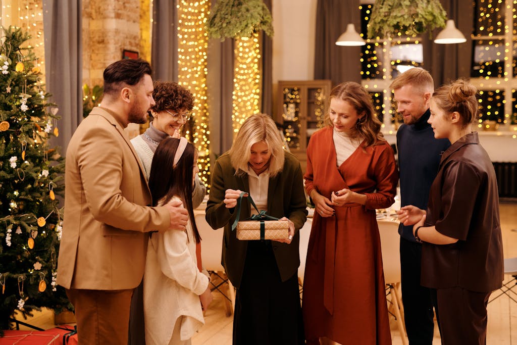 A joyful family gathering around a Christmas tree exchanging gifts indoors, celebrating together.