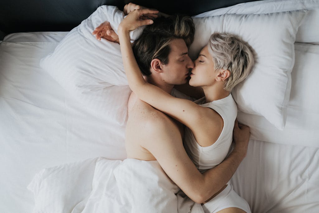 A loving couple sharing an intimate moment in bed, captured from above.