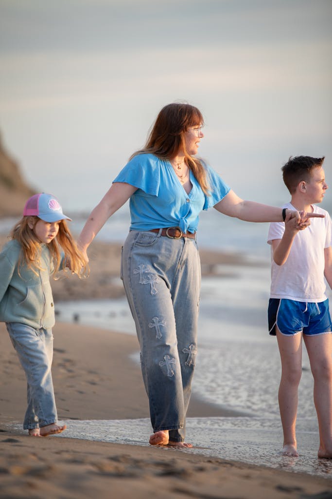 A mother and her children enjoy a peaceful walk along the beach at sunset, embracing family togetherness.