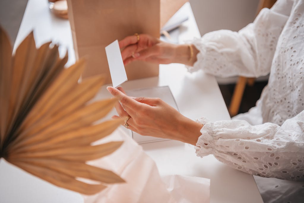A person with lace long sleeves opening a white box at a table.