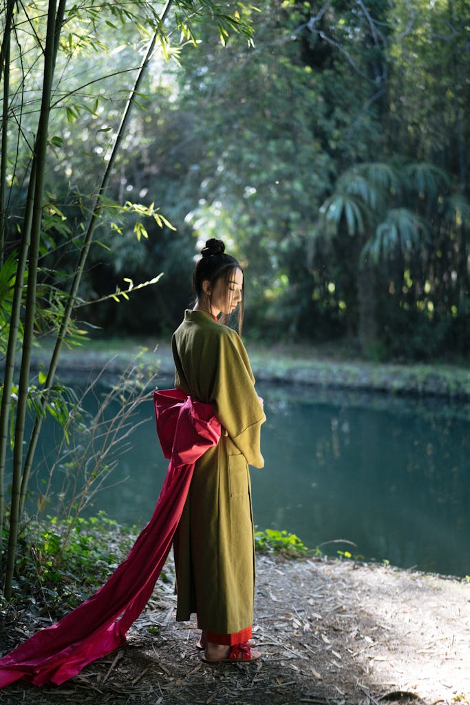 A serene portrait of a Japanese woman in traditional kimono near a peaceful river in spring.