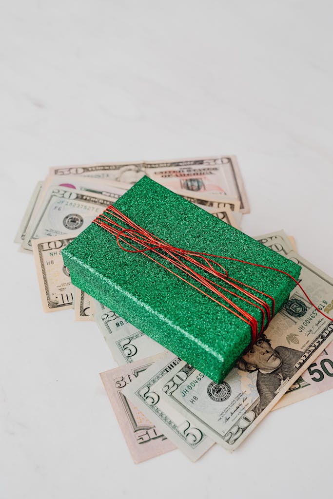 A sparkling green gift box placed on US dollar banknotes, signifying wealth and gifting.
