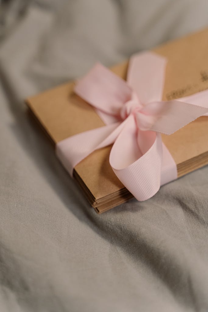 A stack of vintage letters tied with a pink ribbon, resting on soft fabric, evoking nostalgia and romance.