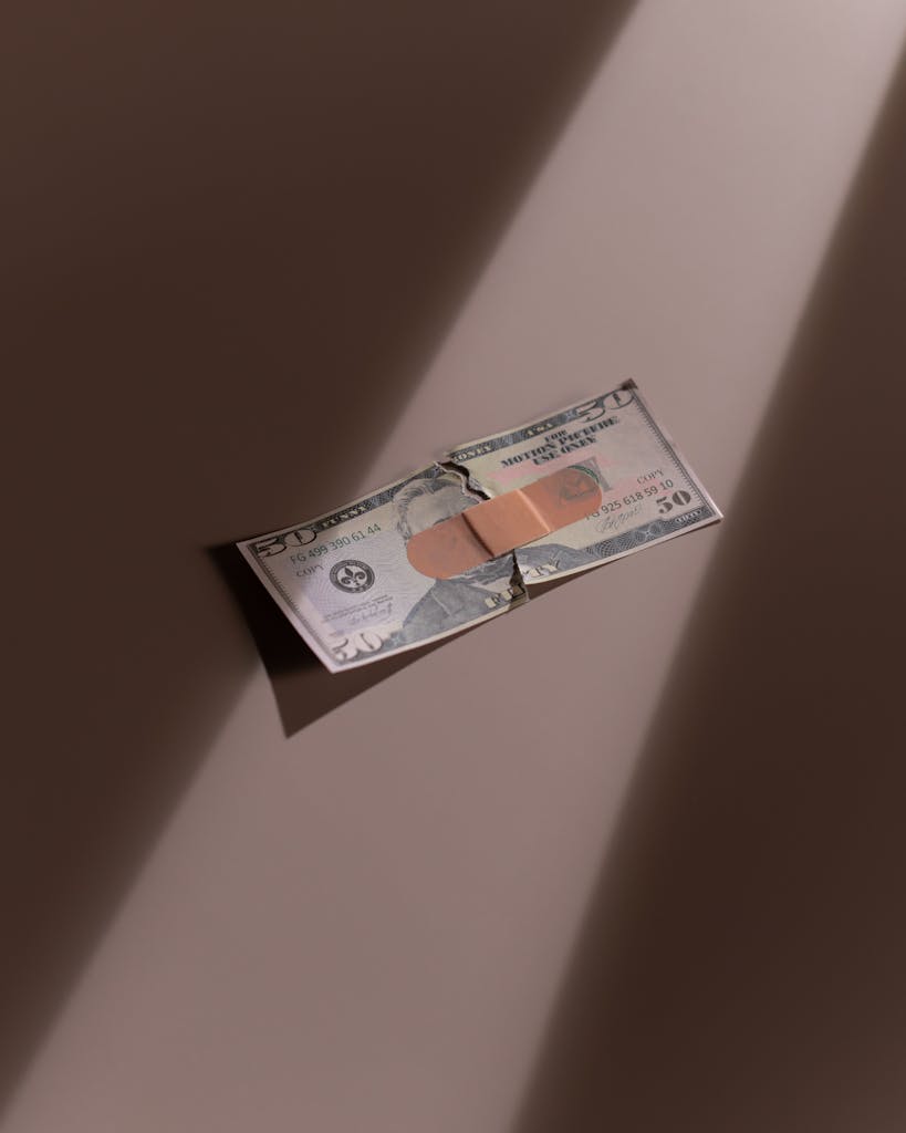 A torn dollar bill patched with a bandage, symbolizing financial recovery.