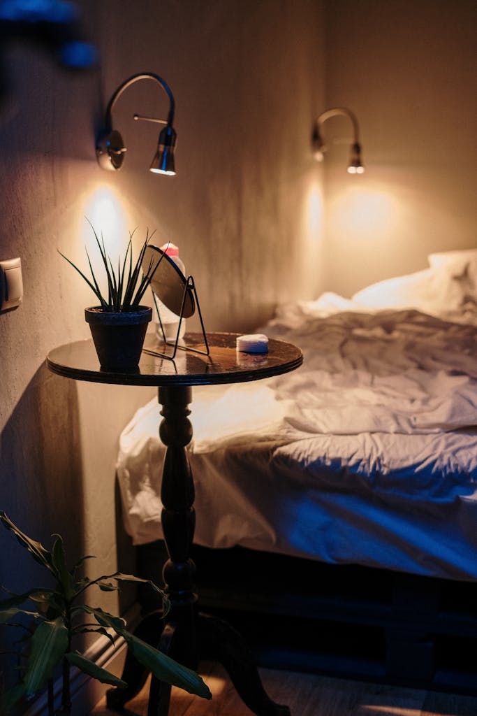 A warm, inviting bedroom with ambient lighting, soft linens, and stylish decor on a side table.