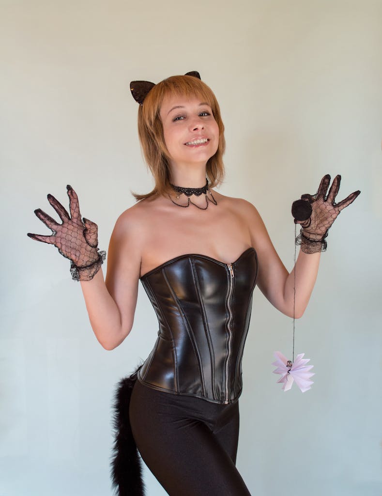 A woman in a cat costume with corset and lace gloves, posing indoors.