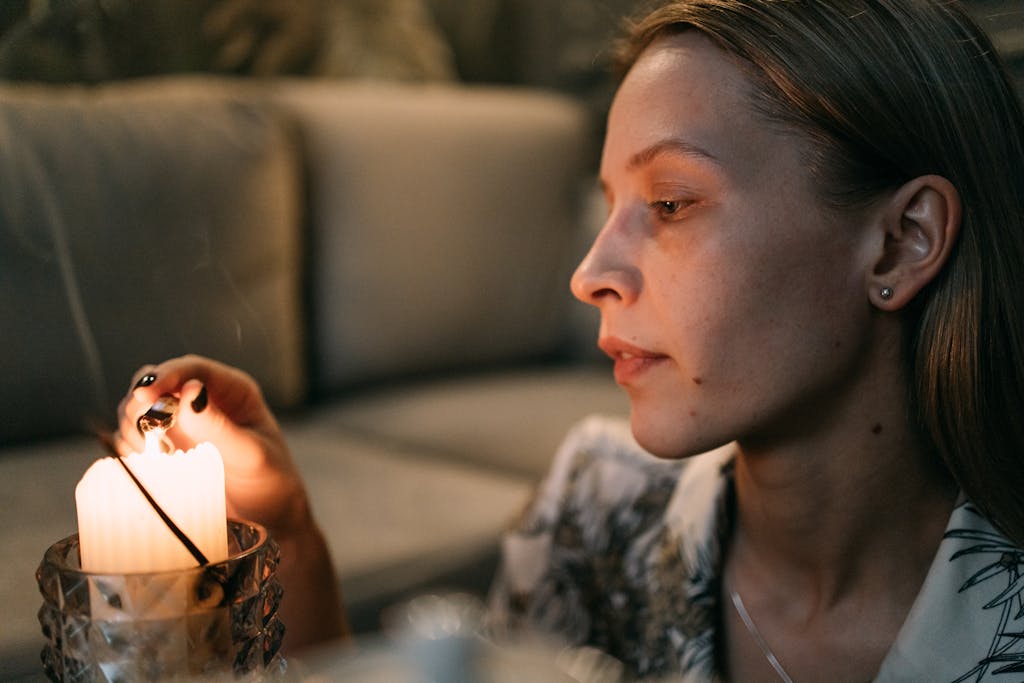A woman performing a calming candle ritual indoors, enhancing the ambient mood lighting.