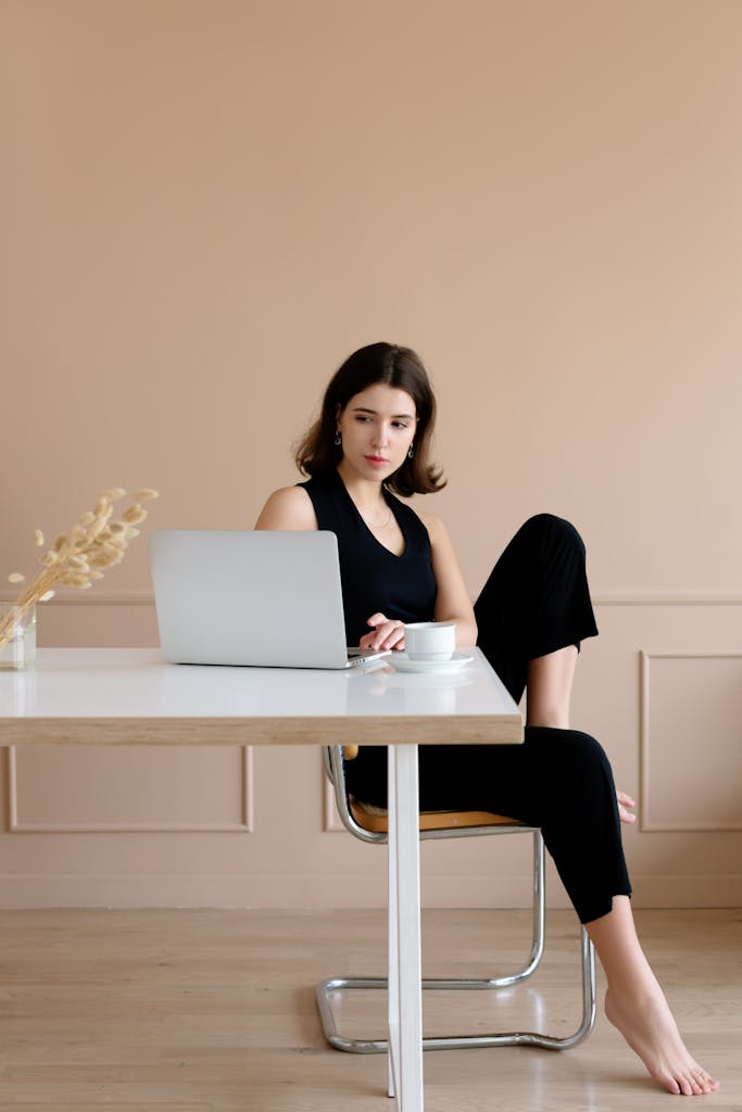 Adult woman working on a laptop in a modern, minimalist indoor setting.