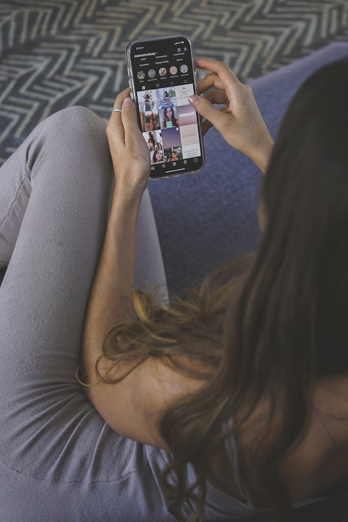 An adult woman browsing social media on a smartphone indoors.