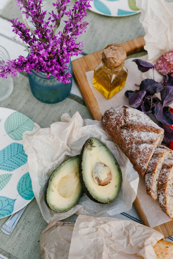An inviting rustic breakfast spread featuring sliced avocado, bread, and decorative flowers, perfect for food enthusiasts.
