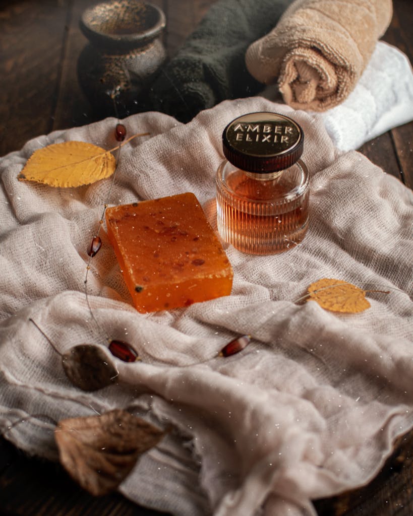 An organic soap bar with amber elixir amidst autumn leaves, towels, and warm tones.