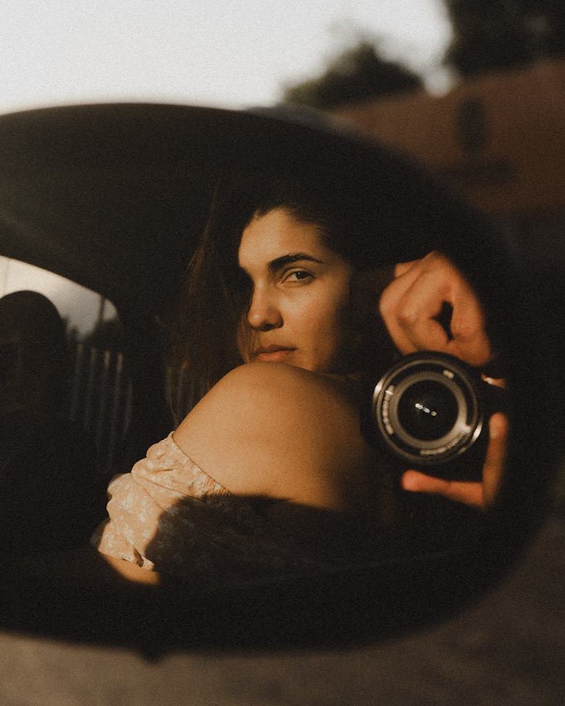 Artistic photo of a woman reflected in a car side mirror with a camera focus.