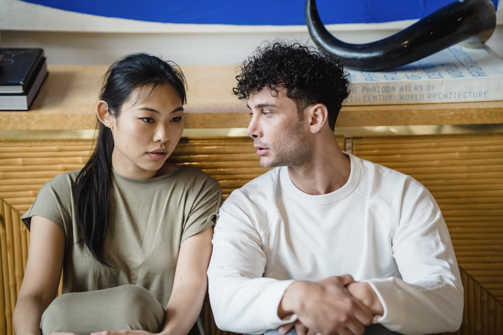 Asian woman and man sitting together having a serious conversation. Indoor setting.