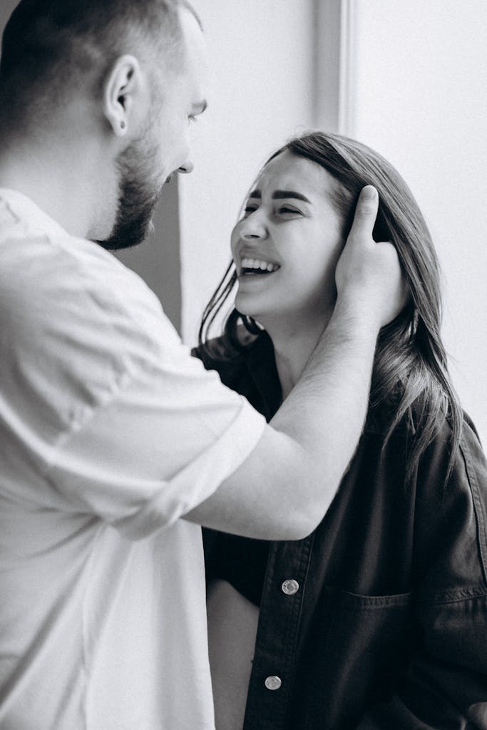 Black and white portrait of a couple laughing and embracing affectionately.