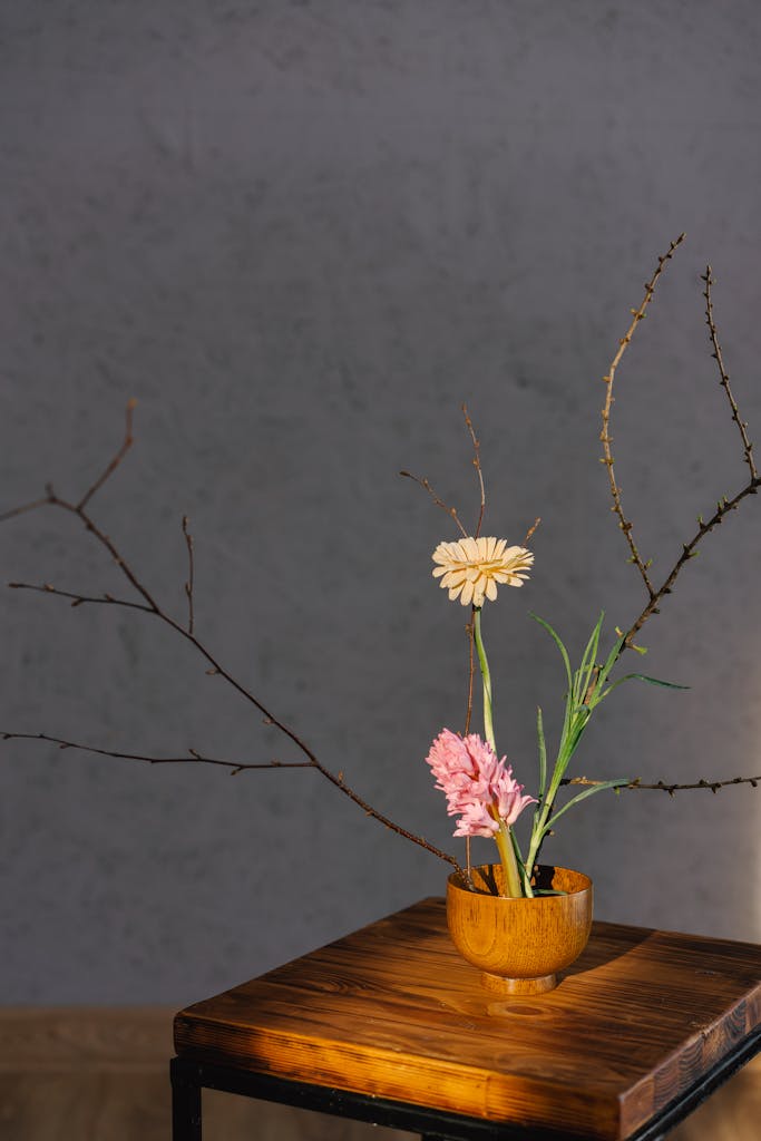 Captivating minimalist flower arrangement in a wooden bowl on a table with gray background.