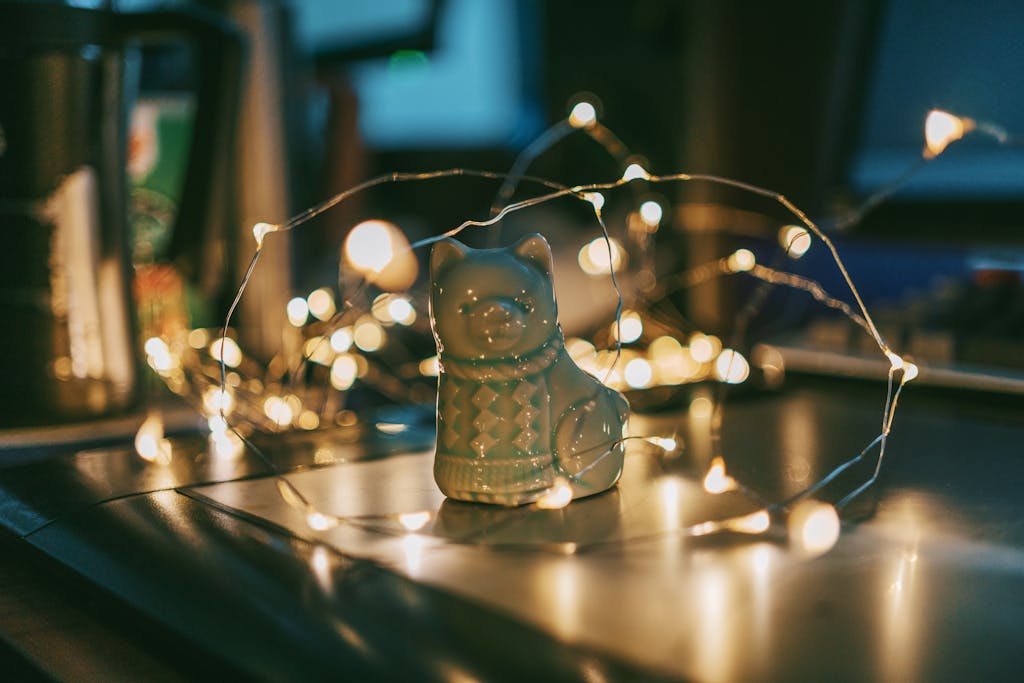 Ceramic bear figurine surrounded by glowing string lights on a table, creating a warm and cozy atmosphere.