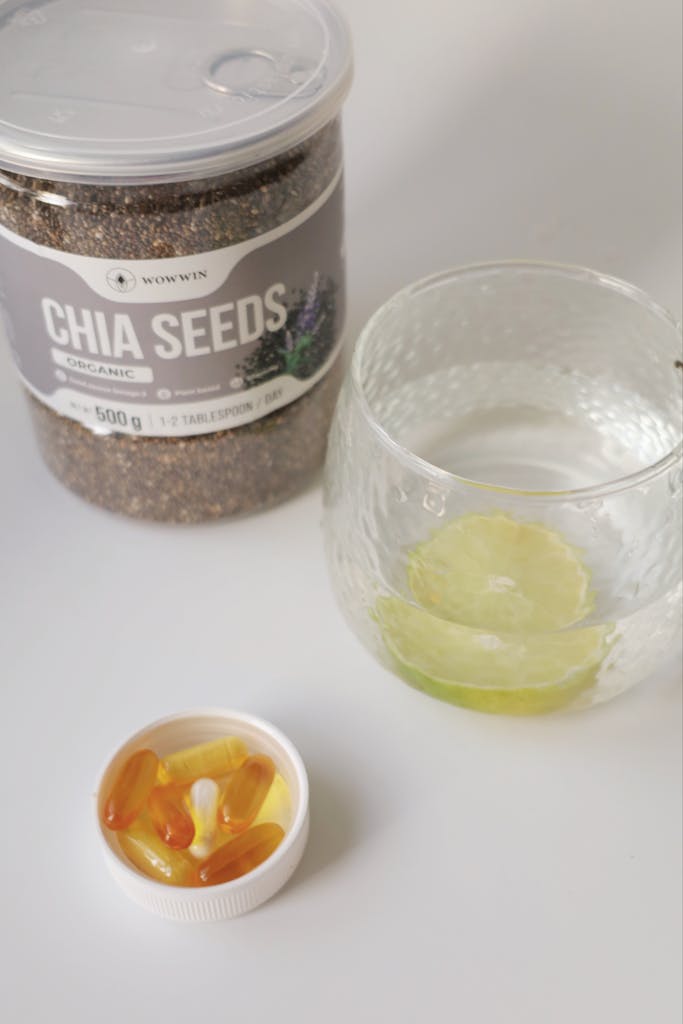 Chia seeds with vitamin capsules and lemon-infused water on a table.