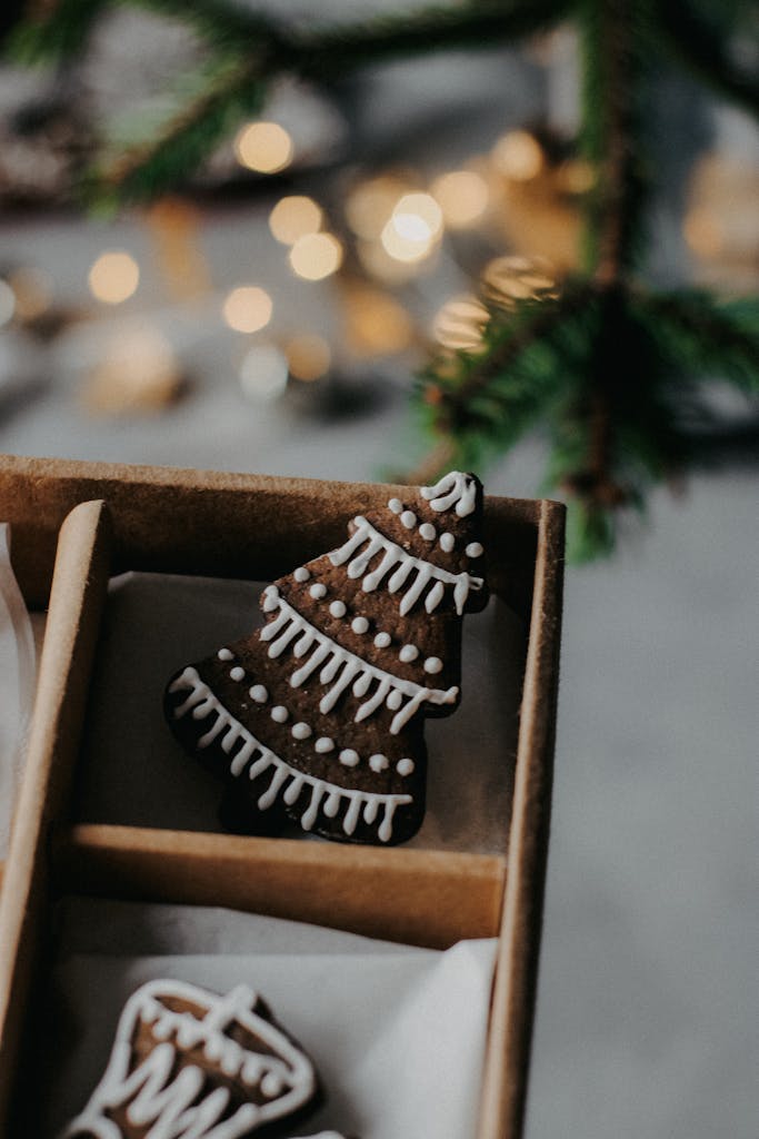 Close-up of a decorated gingerbread cookie shaped like a Christmas tree, placed in a box with holiday ambiance.