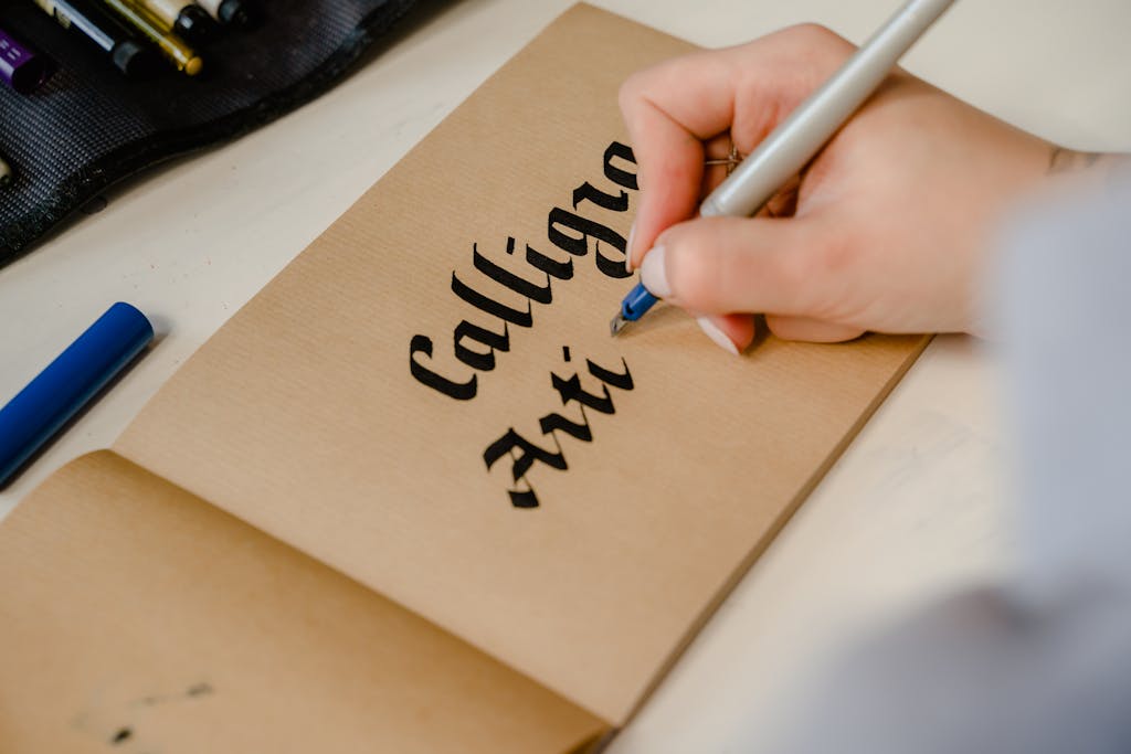 Close-up of a person practicing calligraphy on brown paper indoors.