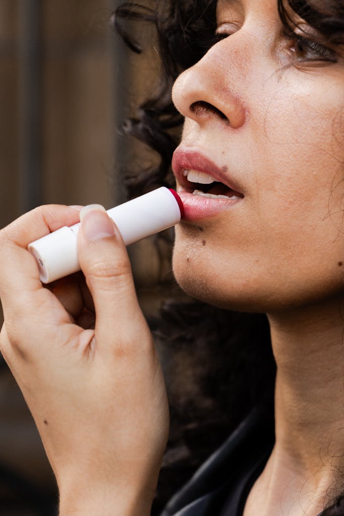 Close-up of a woman applying lip balm, highlighting skincare routine in São Paulo outdoors.