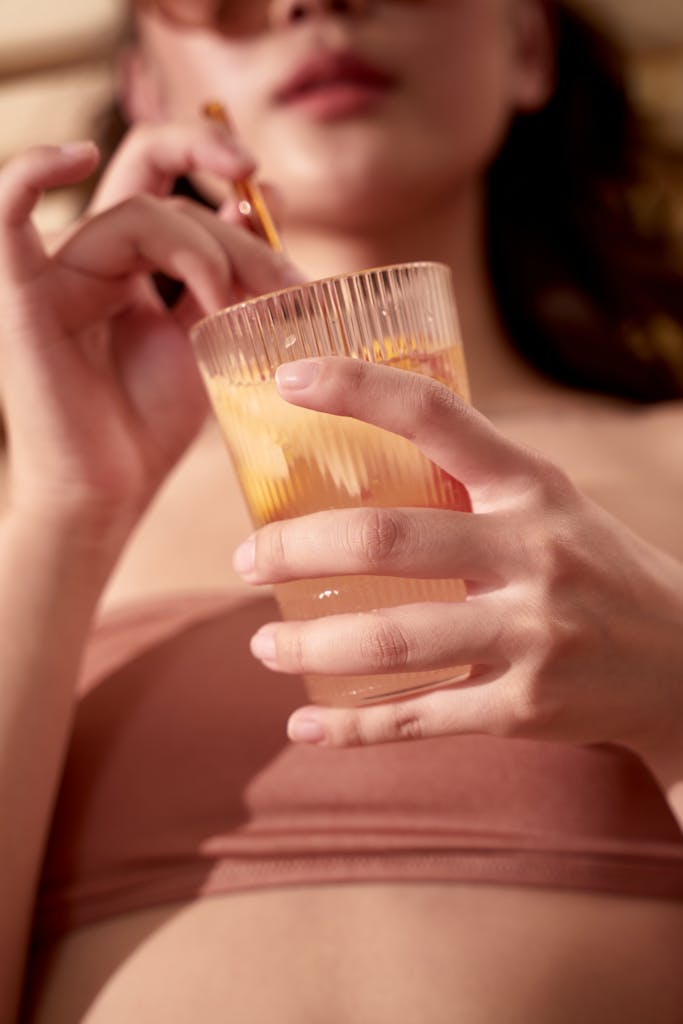 Close-up of a woman holding a refreshing citrus drink outdoors, enjoying a sunny day.