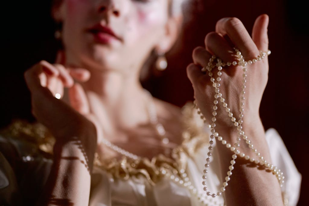Close-up of a woman softly holding a pearl necklace, exuding elegance and grace.