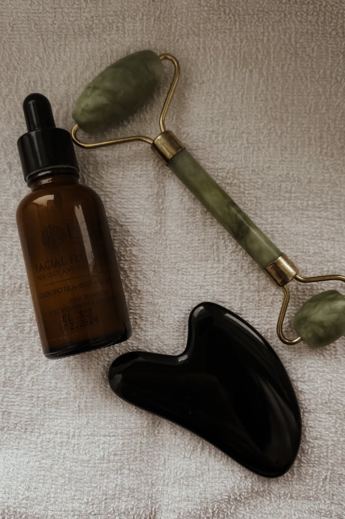 Close-up of jade roller, gua sha tool, and facial serum bottle.