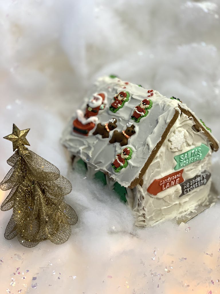 Detailed gingerbread house with festive decor and a glittery tree, perfect for holiday seasons.