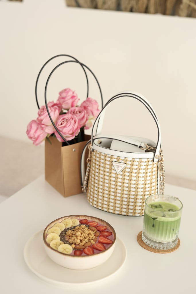 Fashionable breakfast table with fruits, handbag, and flower bouquet.